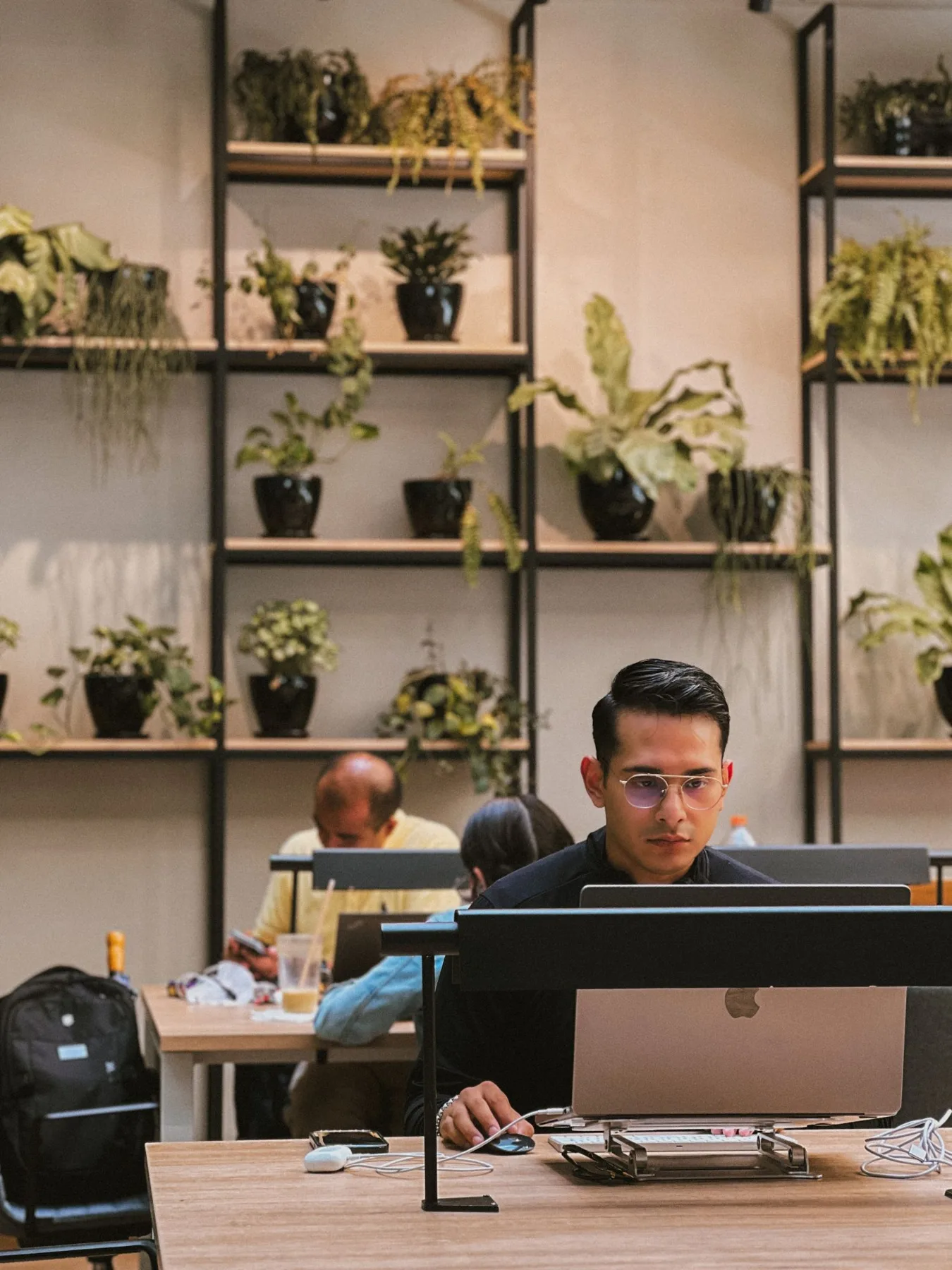 Isaac Lopez trabaja en su laptop en un coworking lleno de plantas
