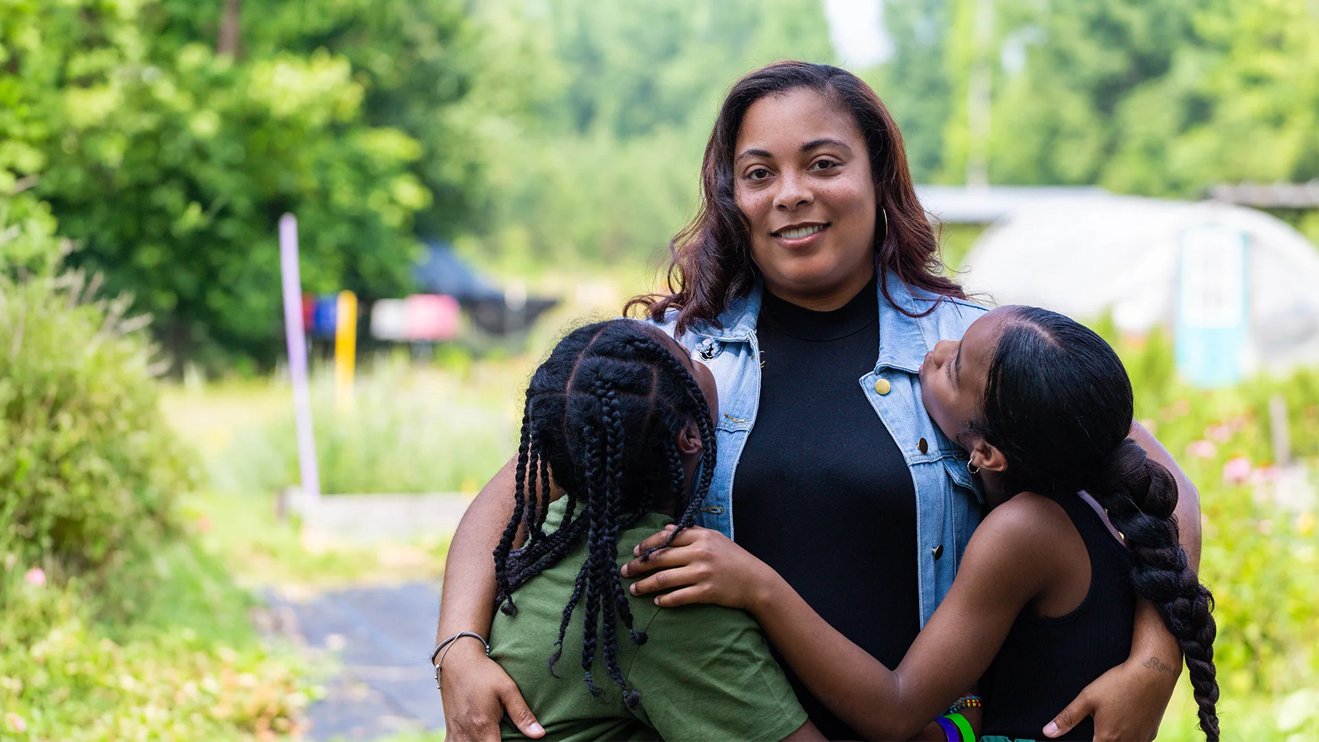 A Benevolence Farm resident hugging her two children outdoors